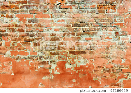 An old red brick wall partly covered with red plaster, partly the bricks are exposed, visible. 97166629