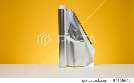 Roll of twisted food foil for packaging food on yellow background Roll of twisted food foil for packaging food on yellow background 97166642