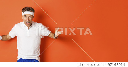 Concept of workout, sports and lifestyle. Portrait of confused middle-aged sportsman complaining, spread hands sideways and looking puzzled, cant understand something, orange background 97167014