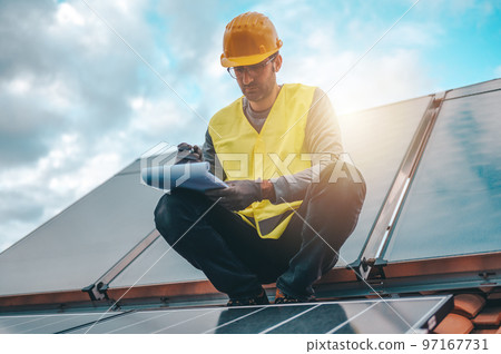 Man works on renewable energy system with solar panel for electricity and hot water 97167731