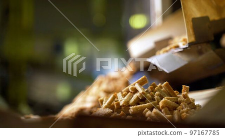 Bread in thin slices in a bakery, shop, supermarket or factory. Automatic slicing of bread for further packaging. Breadcrumbs production technology. Factory for the production of crackers. Bread in thin slices in a bakery, shop, supermarket or factory. Automatic slicing of bread for further packaging. Breadcrumbs production technology. Factory for the production of crackers. 97167785