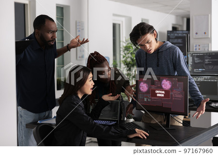 Team of it programmers having web server hacked, looking at critical error on computer monitor in big data office. Diverse software developers trying to solve hacking problem, firewall security. 97167960