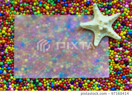 White starfish and a translucent paper for text on a multicolored small bright balls background. Fun playful summer wallpaper. Nautical theme flatly top view. Summertime vacations. Sea ocean animals.  97168414