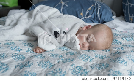 infancy, childhood, development, medicine and health concept - close-up face of sweaty newborn chubby sleeping baby 10 month with pacifier lying on stomach covered with blanket on bed Hot weather infancy, childhood, development, medicine and health concept - close-up face of sweaty newborn chubby sleeping baby 10 month with pacifier lying on stomach covered with blanket on bed Hot weather 97169180