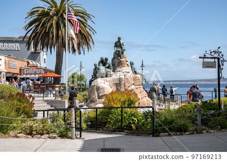 Monterey, USA, September 20, 2022. View of Cannery Row Monument with bronze human sculptures on rocks at coastline of Monterey bay with blue sky in the background during sunny day Monterey, USA, September 20, 2022. View of Cannery Row Monument with bronze human sculptures on rocks at coastline of Monterey bay with blue sky in the background during sunny day 97169213