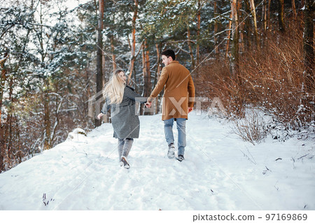 happy young couple walking through the park on a snowy day 97169869