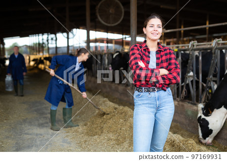 Positive young woman farmer in cowshed 97169931
