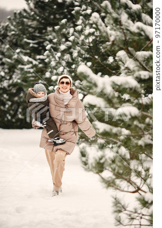 Family in winter clothes on family Christmas vacation. Woman and little boy in a park. People by the pine. Family in winter clothes on family Christmas vacation. Woman and little boy in a park. People by the pine. 97170000