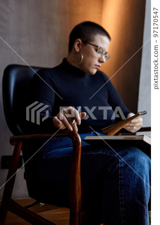 he girl looks at her laptop and makes notes in a notebook he girl looks at her laptop and makes notes in a notebook 97170547