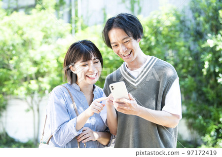 A young couple searching on a smartphone A young couple searching on a smartphone 97172419