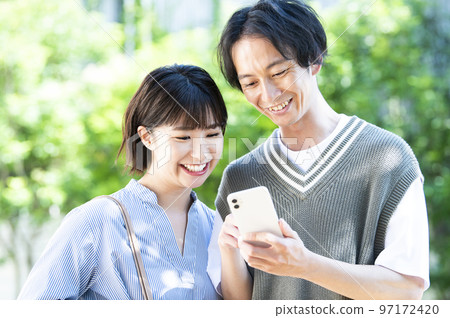 A young couple searching on a smartphone A young couple searching on a smartphone 97172420