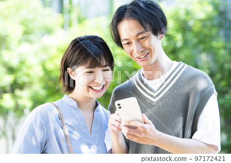 A young couple searching on a smartphone A young couple searching on a smartphone 97172421