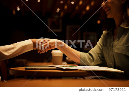 Two Businesswoman shaking hands as sign of successful negotiations. 97172931