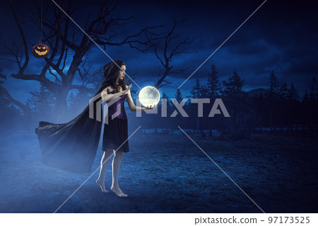 Beautiful young woman in witches hat and costume Beautiful young woman in witches hat and costume 97173525