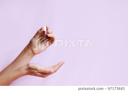 Serum bottle in female hands, side view. Serum bottle in female hands, side view. 97173685