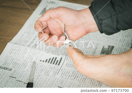 A man cutting his toenails on a newspaper 97173700