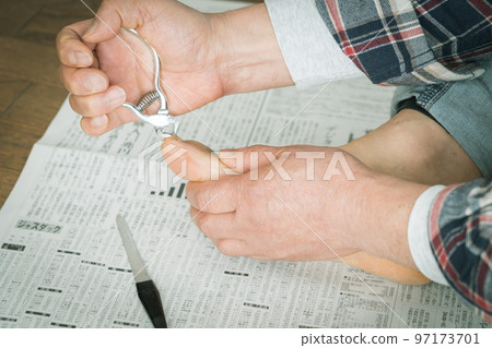 A man cutting his toenails on a newspaper 97173701