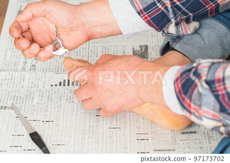 A man cutting his toenails on a newspaper 97173702
