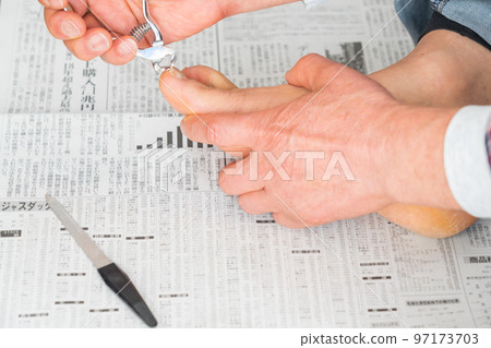 A man cutting his toenails on a newspaper 97173703
