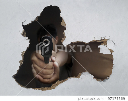 Man holding a gun through a hole in the wall 97175569