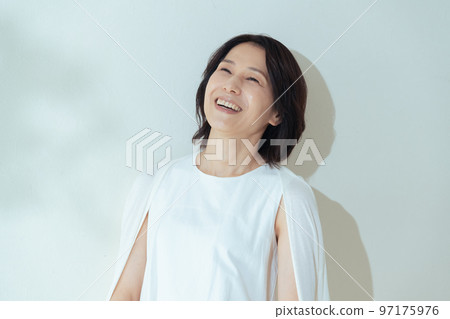 A middle-aged woman laughing in the shade of a summer leaf 97175976