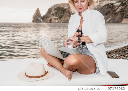 Digital nomad, Business woman working on laptop by the sea. Pretty lady typing on computer by the sea at sunset, makes a business transaction online from a distance. Freelance, remote work on vacation Digital nomad, Business woman working on laptop by the sea. Pretty lady typing on computer by the sea at sunset, makes a business transaction online from a distance. Freelance, remote work on vacation 97176083