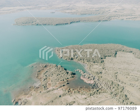 Aerial view on mountain lake. Drone over water reservoir at mountain valley covered with green spring forest. Beautiful view from above on smooth blue surface of mountain lake among highlands. Nobody Aerial view on mountain lake. Drone over water reservoir at mountain valley covered with green spring forest. Beautiful view from above on smooth blue surface of mountain lake among highlands. Nobody 97176089