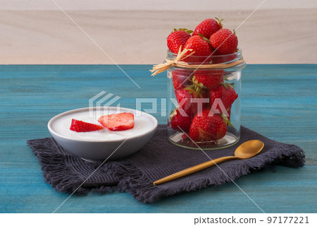 Bowl of yogurt with fresh organic strawberries on blue background 97177221
