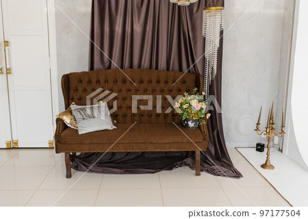 Luxury brown classic sofa with pillows and a bouquet of flowers in a vase in the living room of the house Luxury brown classic sofa with pillows and a bouquet of flowers in a vase in the living room of the house 97177504