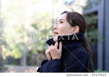 一個女人因為冬天很冷,把外套的領子豎起來 一個女人因為冬天很冷,把外套的領子豎起來 97177625