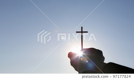The brightly shining sun and the holy cross symbolizing the death and resurrection of Jesus Christ held in both hands The brightly shining sun and the holy cross symbolizing the death and resurrection of Jesus Christ held in both hands 97177824