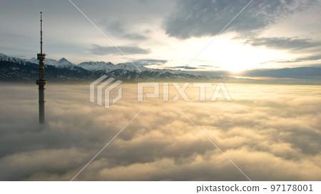 The TV tower looks out of the clouds at sunset. 97178001
