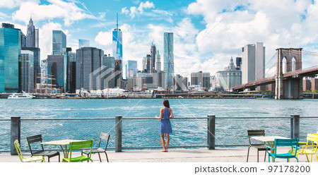 New York city Manhattan skyline seen from Brooklyn waterfront - woman looking at view. American people walking enjoying view of Manhattan over the Hudson river from the Brooklyn side. NYC cityscape New York city Manhattan skyline seen from Brooklyn waterfront - woman looking at view. American people walking enjoying view of Manhattan over the Hudson river from the Brooklyn side. NYC cityscape 97178200