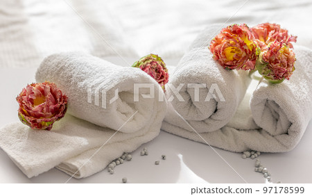 Close-up, white terry bath towels and flowers. 97178599