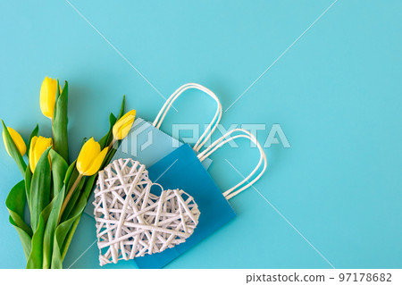 Flat lay blue background with flowers and paper bags. Flat lay blue background with flowers and paper bags. 97178682