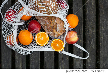 Fruits and bread in a shopping bag on a wooden background. Fruits and bread in a shopping bag on a wooden background. 97178793