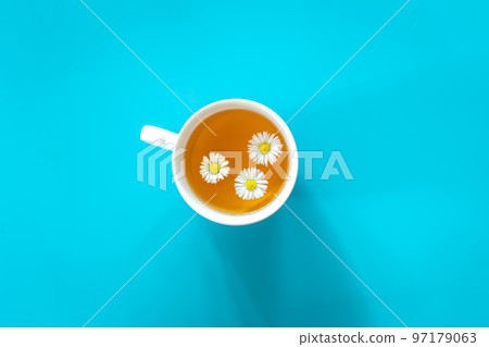 A cup of chamomile tea on blue background, flat lay. A cup of chamomile tea on blue background, flat lay. 97179063
