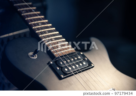 Close-up, black electric guitar on a dark background. Close-up, black electric guitar on a dark background. 97179434