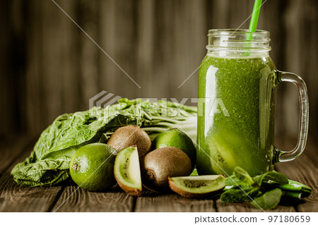 Front view of green smoothie in glass jar and ingredients on wooden background. Healthy eating  97180659