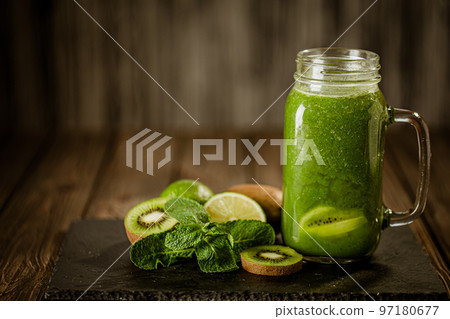 Front view of green smoothie in glass jar and ingredients on wooden background. Good food concept Front view of green smoothie in glass jar and ingredients on wooden background. Good food concept 97180677