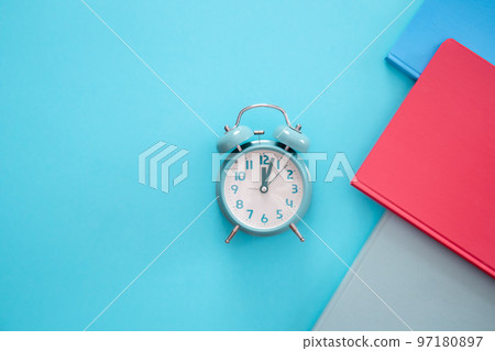 Alarm clock and notepads on a blue background, flat lay. Alarm clock and notepads on a blue background, flat lay. 97180897