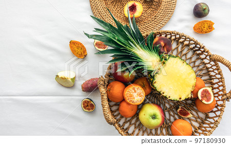 Pineapple and other exotic fruits in a basket on a white background, top view. 97180930