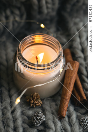 Close-up, candle and cinnamon sticks on the background of a gray knitted element. Close-up, candle and cinnamon sticks on the background of a gray knitted element. 97181482