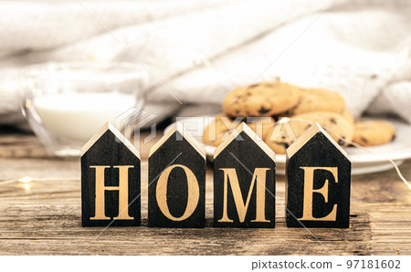 Decorative word home on a blurred background with a glass of milk and cookies.. Decorative word home on a blurred background with a glass of milk and cookies.. 97181602