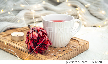 Cozy composition with a cup of red tea and an exotic flower in bed. 97182056