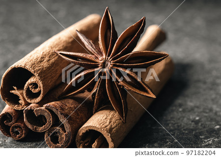 Aromatic cinnamon sticks and anise on black table, close up. 97182204