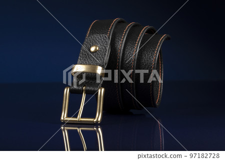 Black leather belt on a dark blue background. 97182728