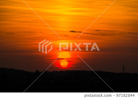 The bright red sun sets over the horizon 97182844
