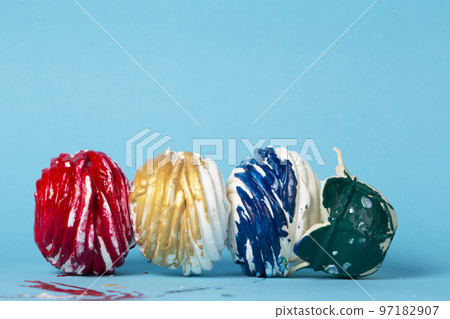 Colorful cake or marshmallow covered with multi-colored icing dropped on a blue background. Creative sweet food. Beautiful unusual dessert. Colorful cake or marshmallow covered with multi-colored icing dropped on a blue background. Creative sweet food. Beautiful unusual dessert. 97182907