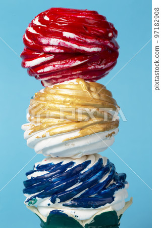 Colorful cake or marshmallow covered with multi-colored icing on a blue background. Creative sweet food. Beautiful unusual dessert. Colorful cake or marshmallow covered with multi-colored icing on a blue background. Creative sweet food. Beautiful unusual dessert. 97182908